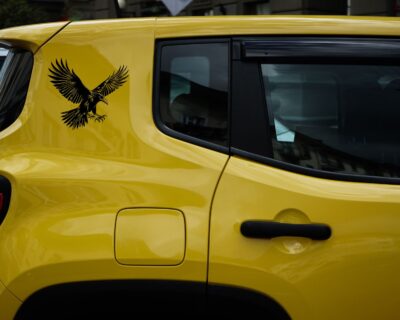 Striking black silhouette vinyl decal of a raven in mid-flight, wings spread wide and talons extended.