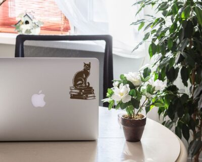 Vinyl decal of a cat sitting gracefully on a stack of books, rendered in a bold silhouette style.