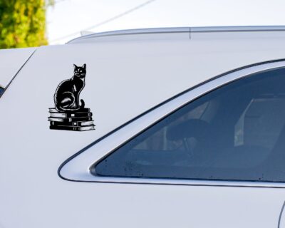 Vinyl decal of a cat sitting gracefully on a stack of books, rendered in a bold silhouette style.